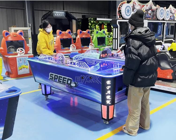 Dos jugadores utilizando la mesa de hockey de aire que funciona con monedas en una sala de exposición.