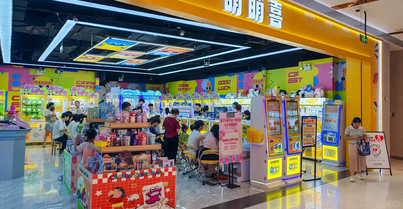 Open-front shopping mall prize store with machines, payment kiosks and customers